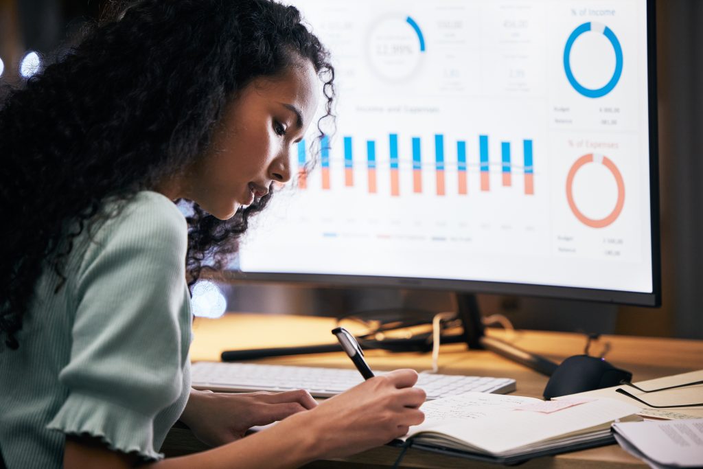 Business woman, night and computer screen, data analysis with analytics, notes and productivity at .